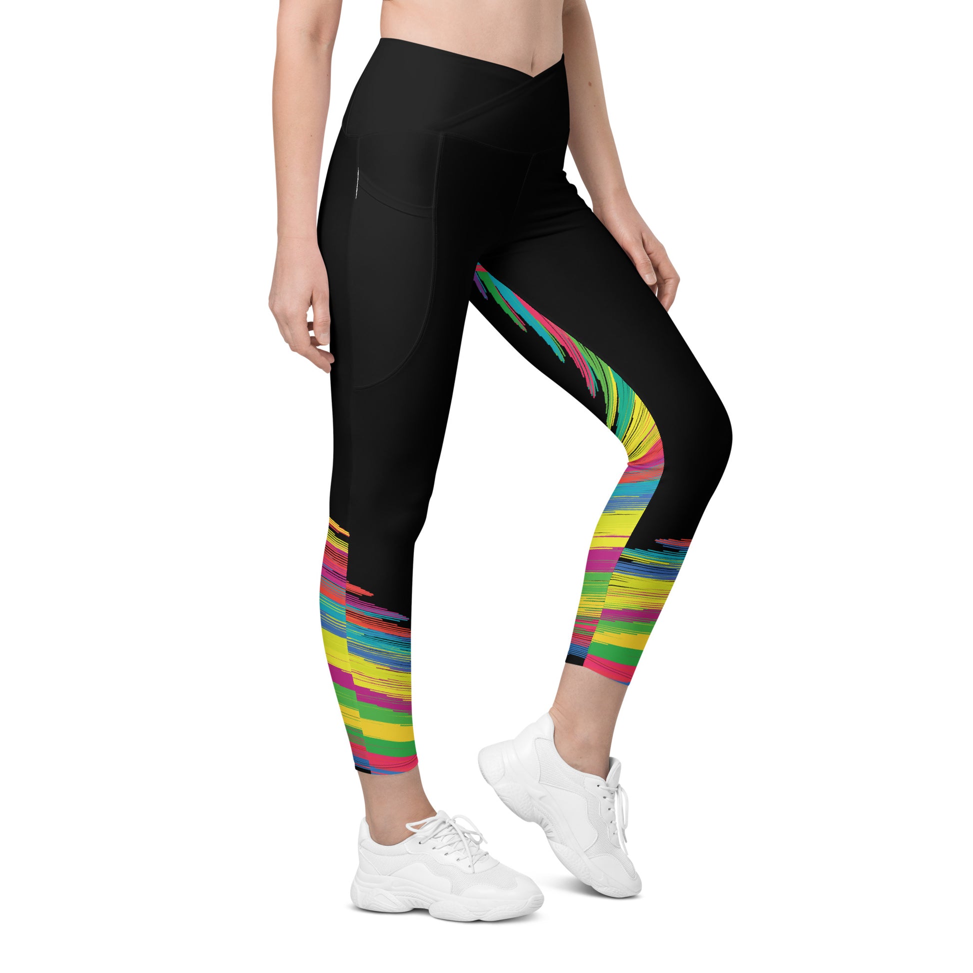 Front view of woman wearing black crossover leggings with colorful brushstroke pattern on the lower legs and side pockets