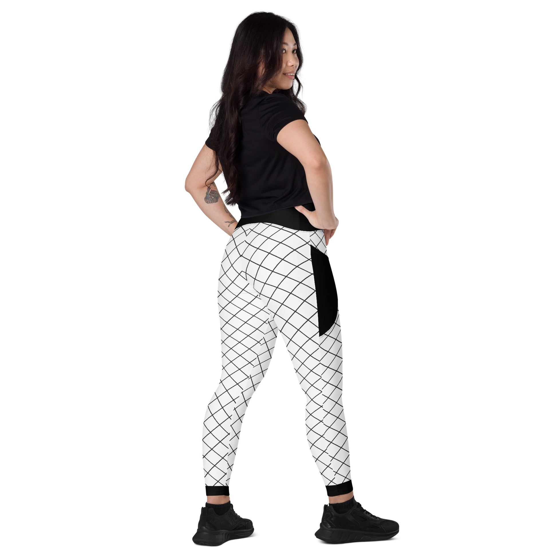 Front view of woman wearing black and white geometric grid leggings with pockets and black waistband