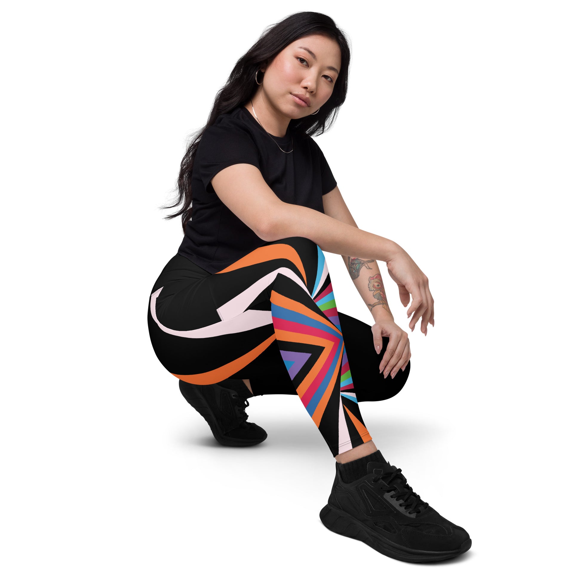 Woman crouching in black geometric leggings with bright orange, pink, blue, green and purple abstract design
