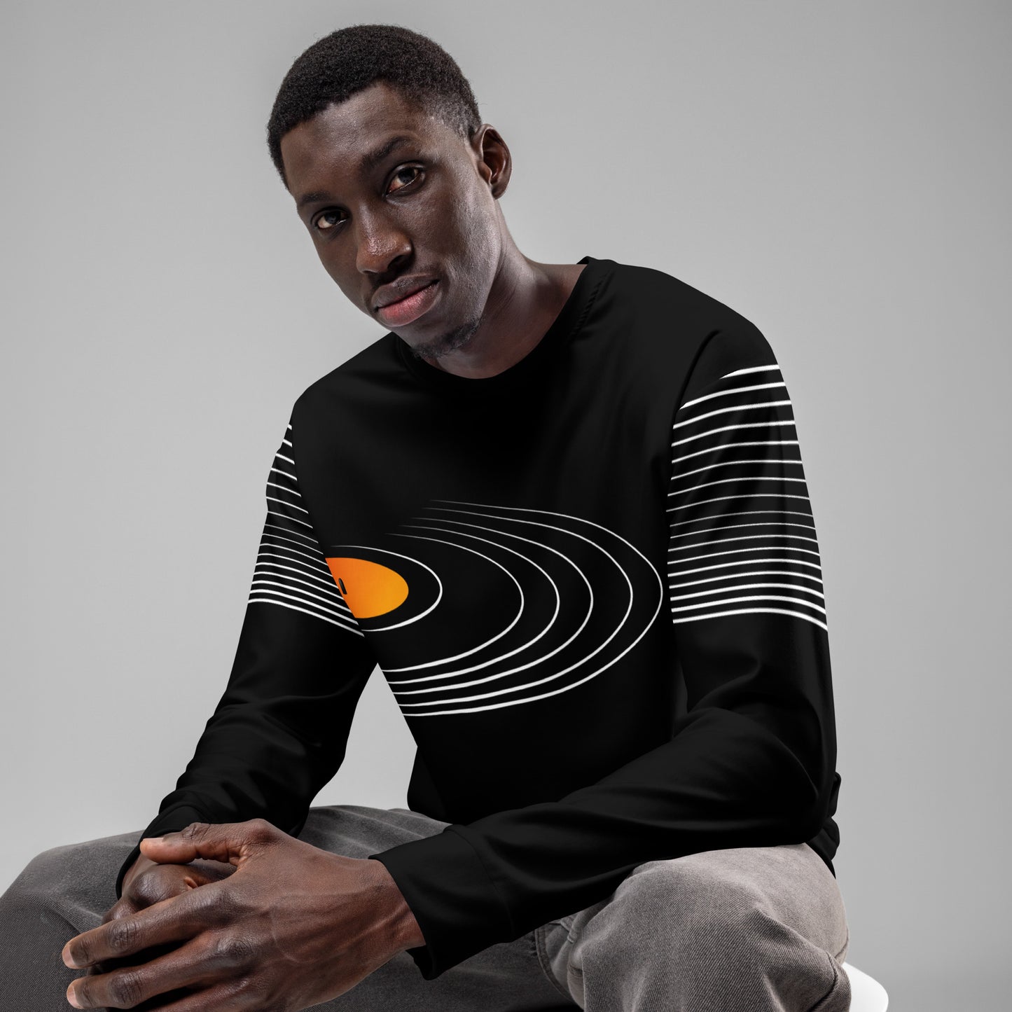 Man wearing a black retro vinyl record groove unisex sweatshirt with white concentric lines and orange center detail