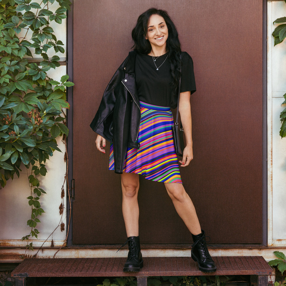 Woman styling colorful striped skater skirt with black top and black boots