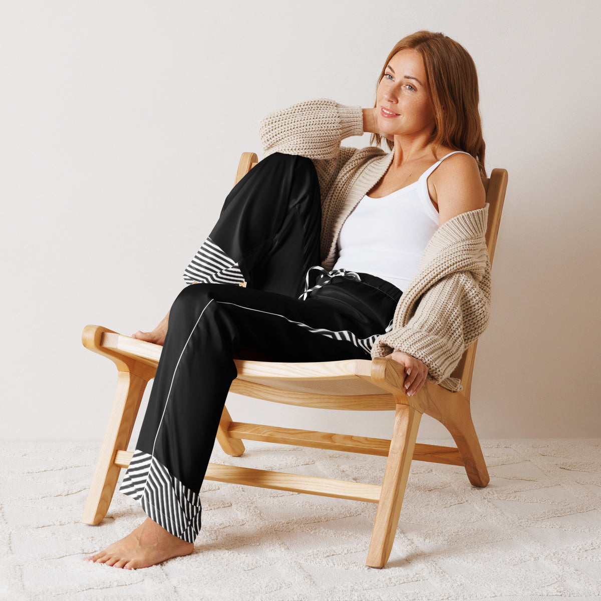 Woman relaxing in black women's pajama pants with monochrome striped cuff details