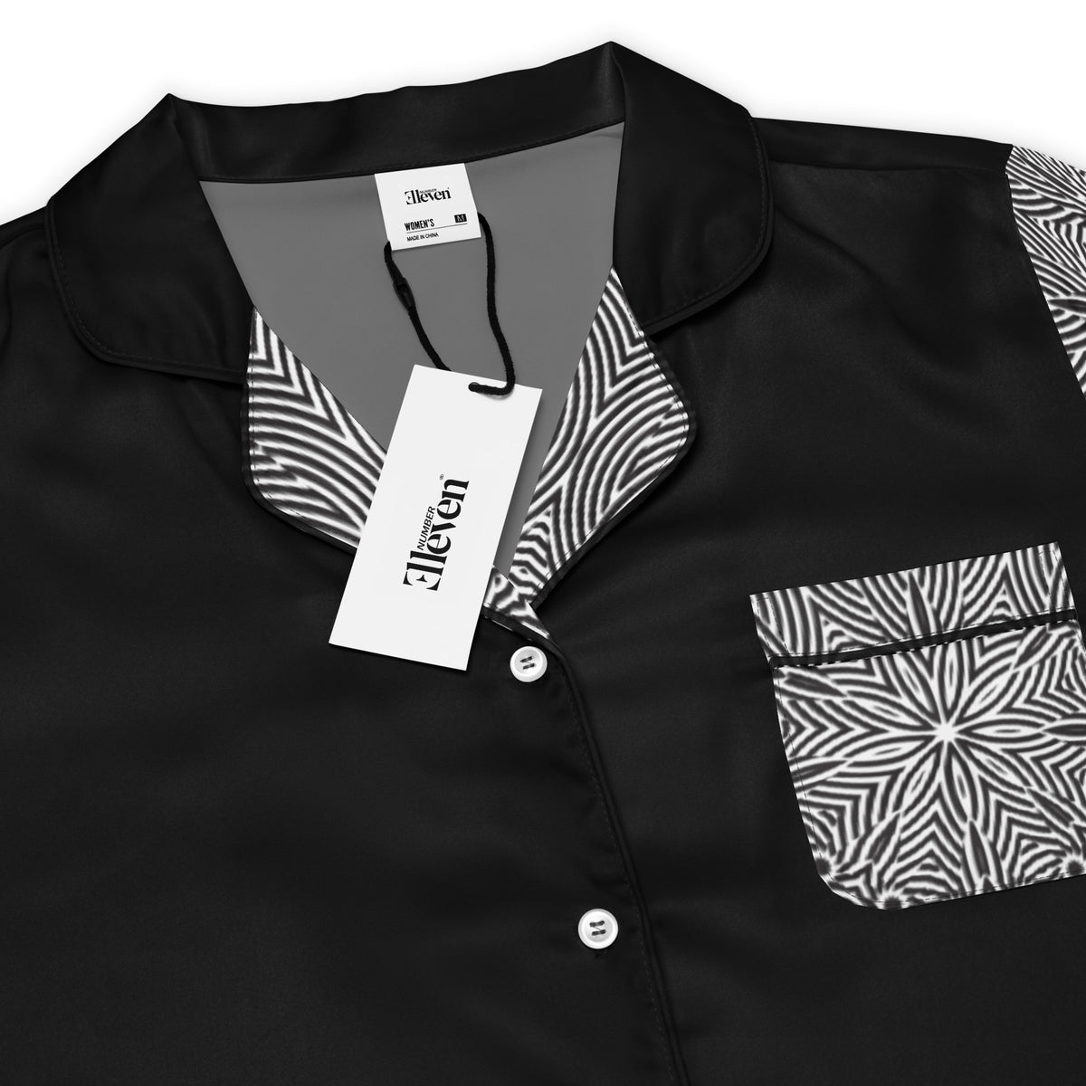 Close-up of black women's pajama top with white piping patterned collar and floral chest pocket