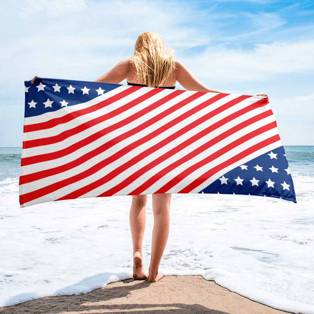 Woman holding an American stars and stripes beach towel horizontally by the sea