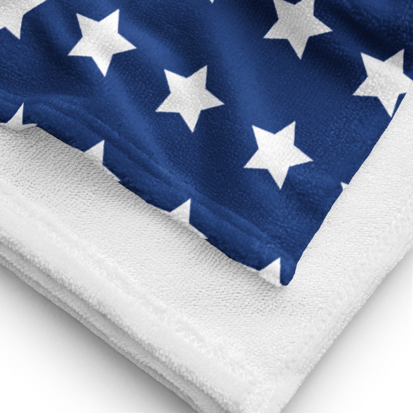 Close-up detail of American stars and stripes beach towel showing printed blue star pattern and white terry backing