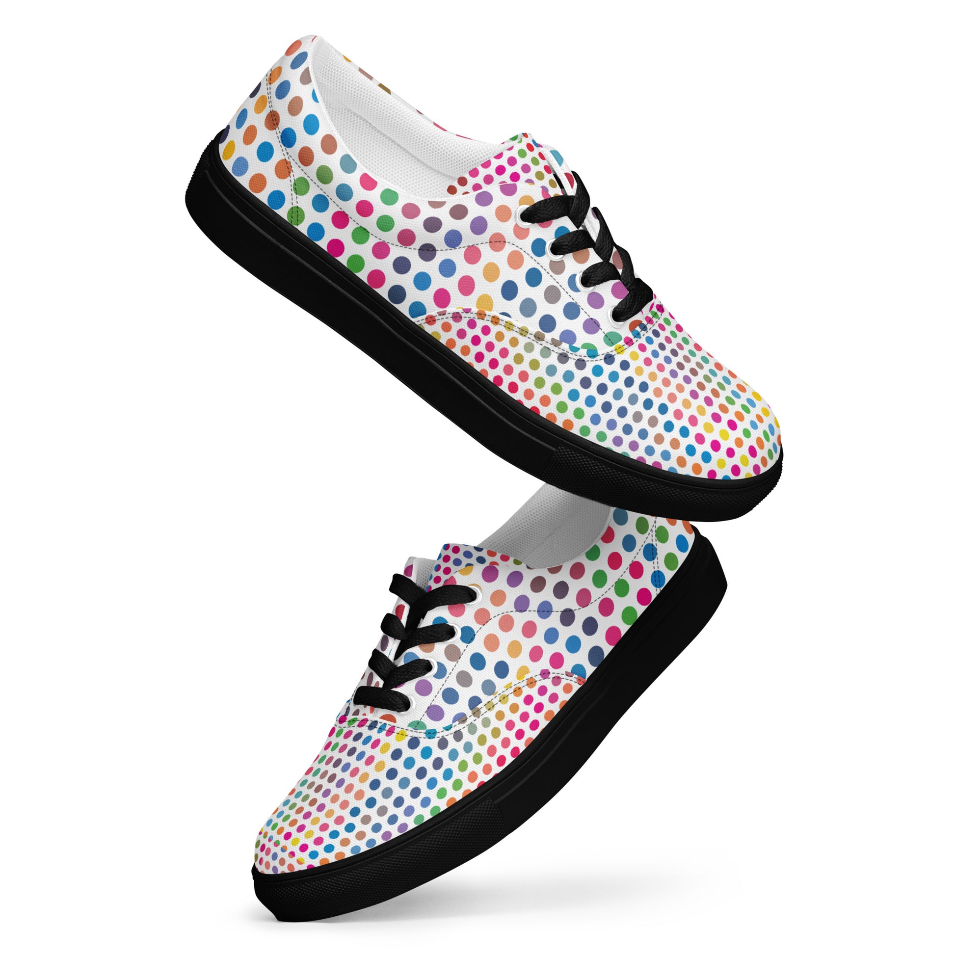 Floating pair of women’s lace-up canvas shoes with black sole and colorful polka dot design